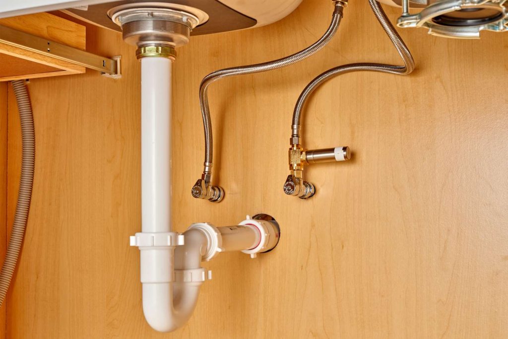 Plumber Using Hose To Suction Water Under Apartment Building